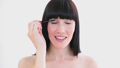 mujer feliz aplicando máscara en sus pestañas