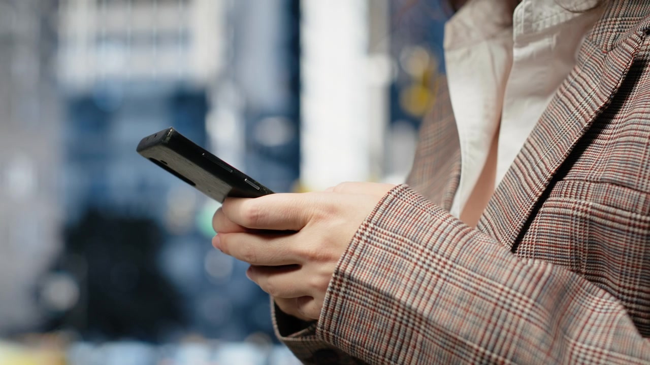 Primo piano di smartphone tenuto nelle mani di una donna d'affari su una strada cittadina.