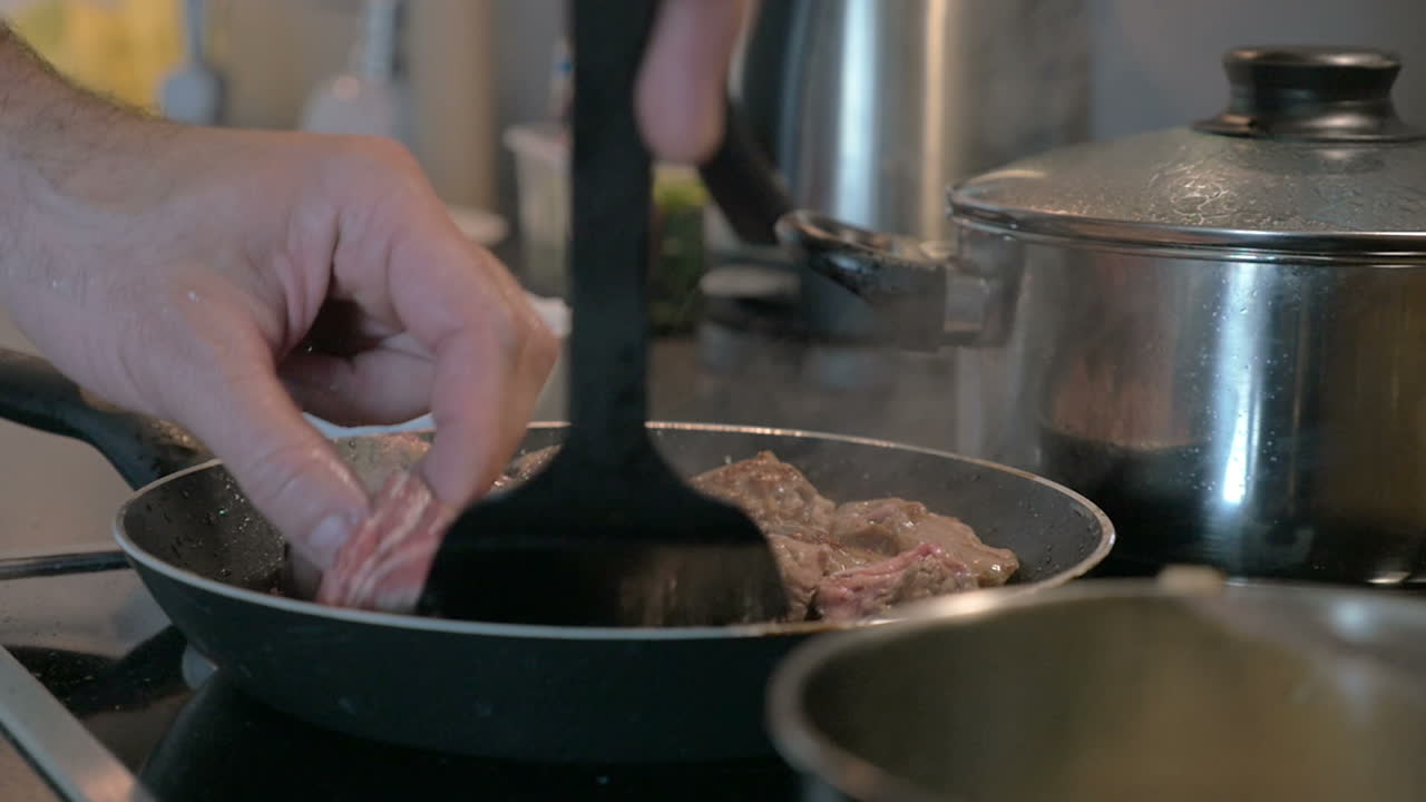 hombre girando la carne en la sartén