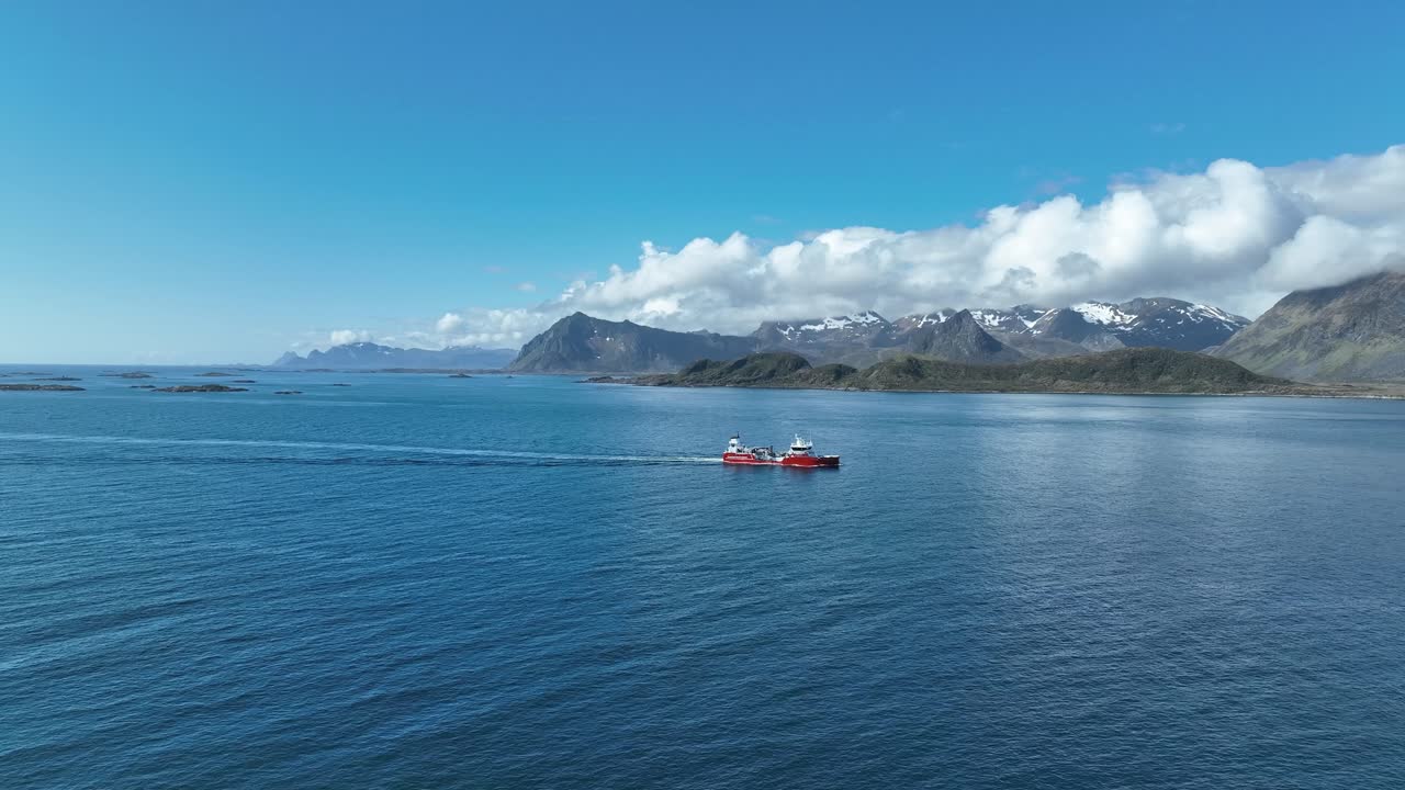 Well boat moves in Gimsoystraumen, passing shoreline and fjære before sailing with Lofoten peaks