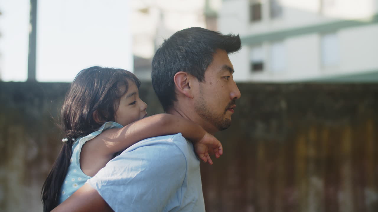 뒤에 그의 딸을 들고 행복 한 아시아 남자의 측면 보기