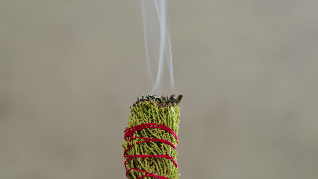 Person holding Palo Santo wood stick in hand, aromatic Palo Santo burning on black background, smoke spreading around, slow motion video clip, high quality 4k close up footage. High quality 4k footage