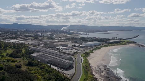 aerial trucking pan over highway along coast in industrial zone of port kembla nsw australia