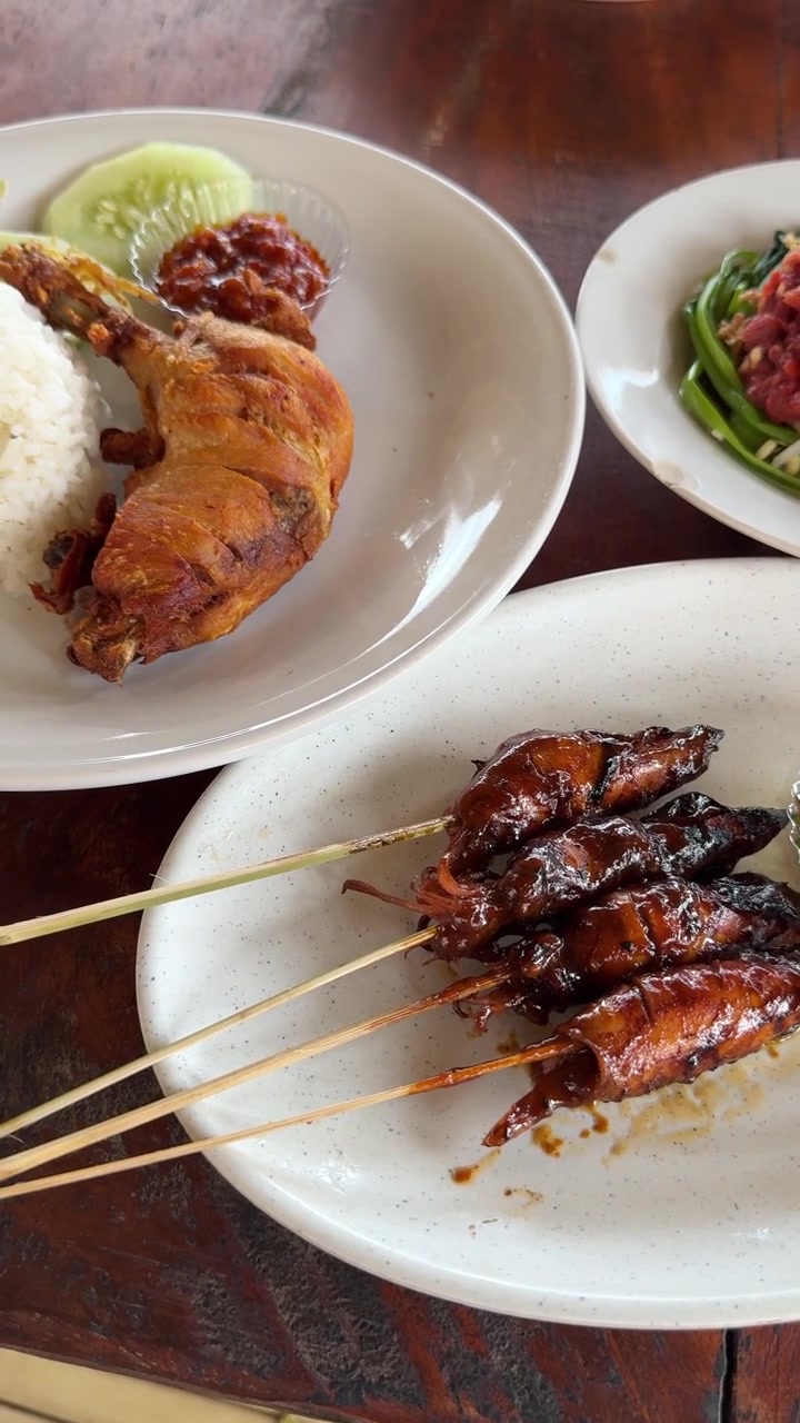 Perinteinen indonesialainen ateria grillattujen mustekalavartaiden ja paistetun kanan kera.