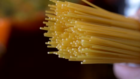 raw spaghetti are held by one hand