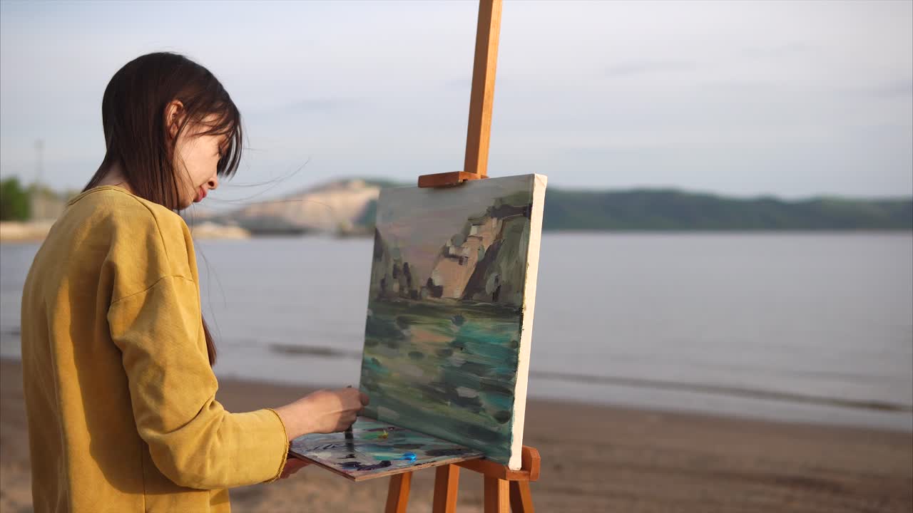 Woman painting a landscape at the beach