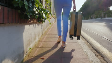 woman tourist walking on the road with a travel bag back view