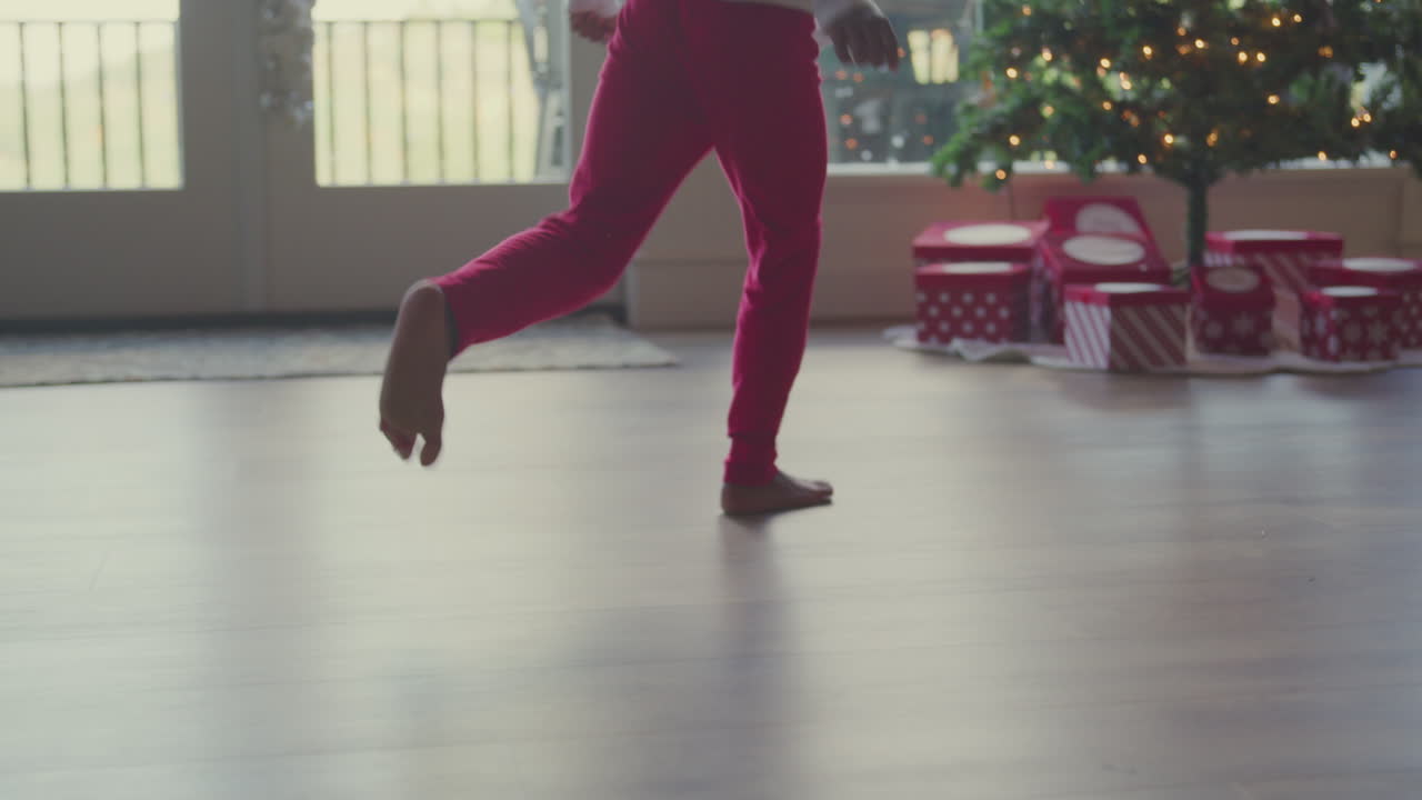 Child runs across floor toward presents under christmas tree