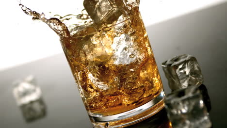 ice falling into tumbler of whiskey and ice