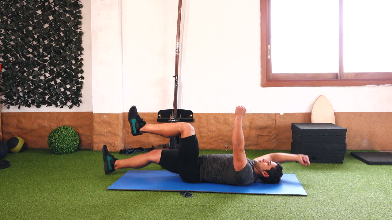 variación del ejercicio abdominal con entrenador muscular sobre alfombra azul