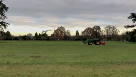 un tractor recorta la hierba en un campo de fútbol en bury st edmunds, suffolk