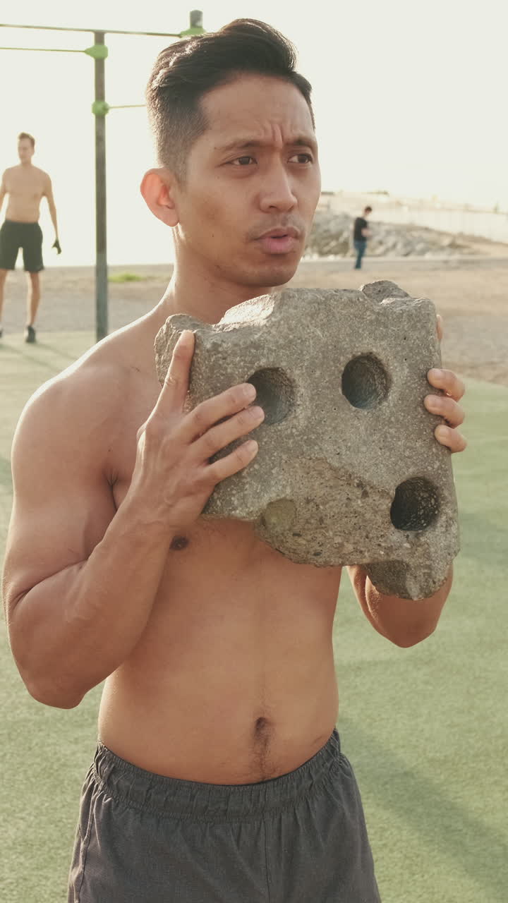 Shirtless man lifting a stone