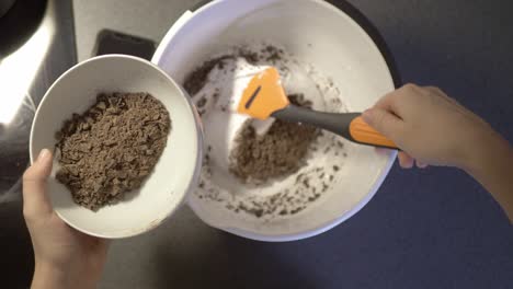 top down view above person stirring healthy yogurt mixture around in white kitchen bowl for healthy breakfast