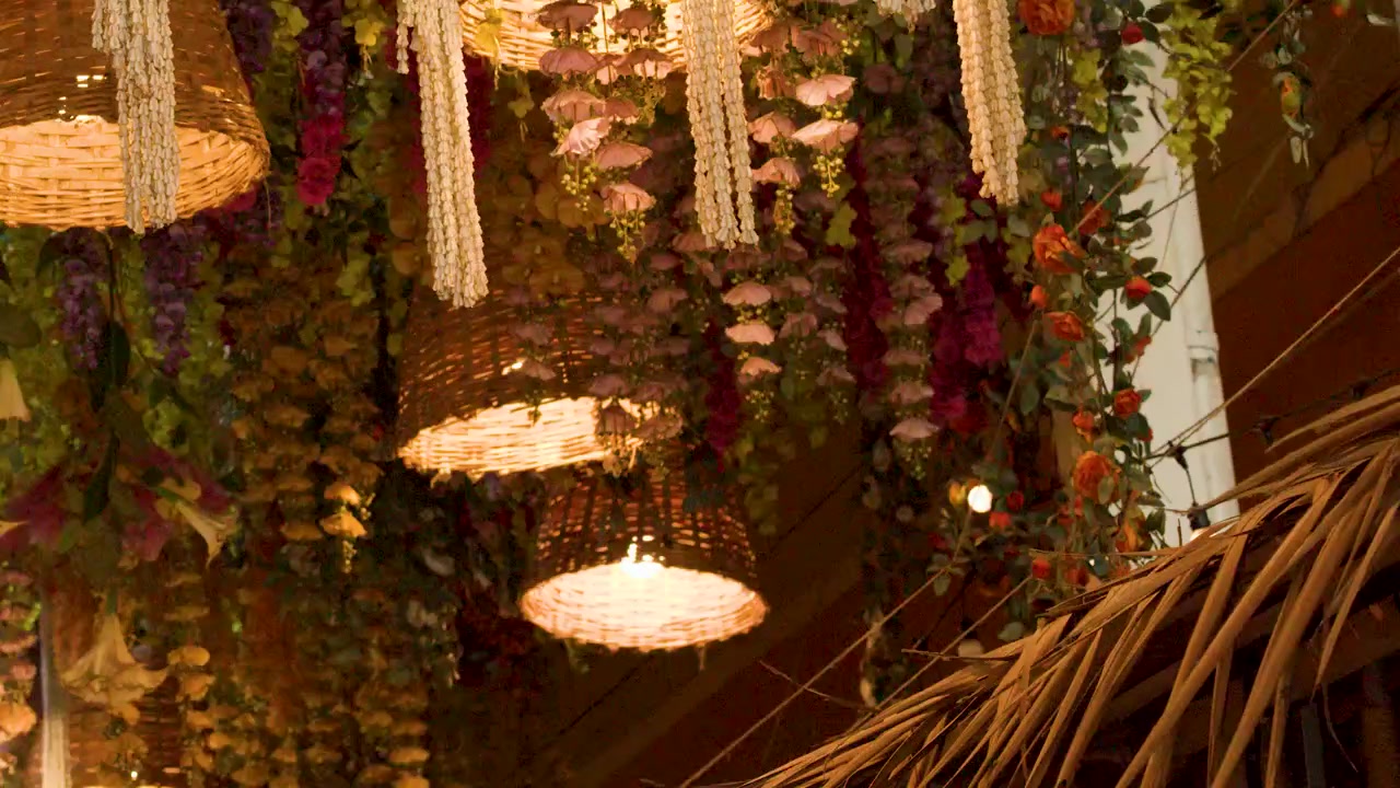 Lampade a cesto intrecciate appese in un arredamento floreale tropicale.