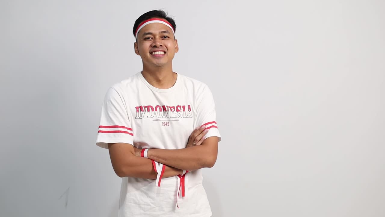A confident Asian man with red white ribbon, standing with arms folded, looking at the camera isolated over white background
