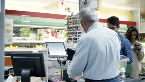 cashier and buyers at cash register in supermarket