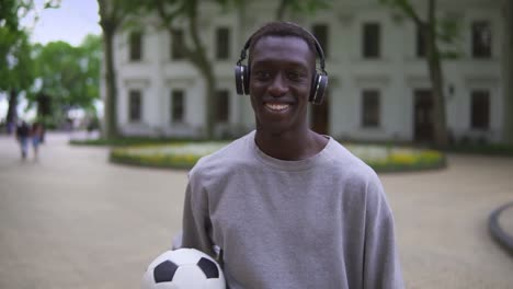 Football-Player-Stands-Holding-A-Football-Ball-On-An-Old-City-Street