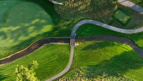 top down view of luxury golf course with small creek and bridge