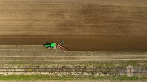 drone de arriba hacia abajo visión general seguimiento sigue tractor arado y riego campo