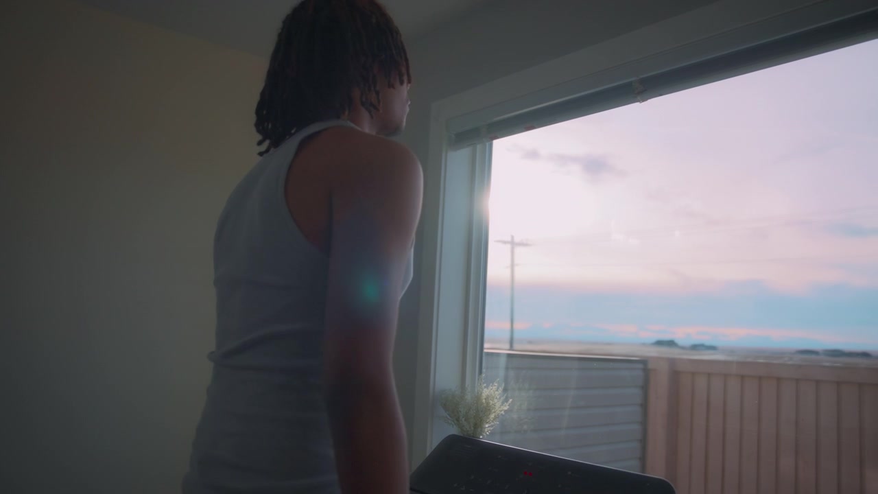 Uomo con i dreadlock che cammina su un tapis roulant con vista sul tramonto