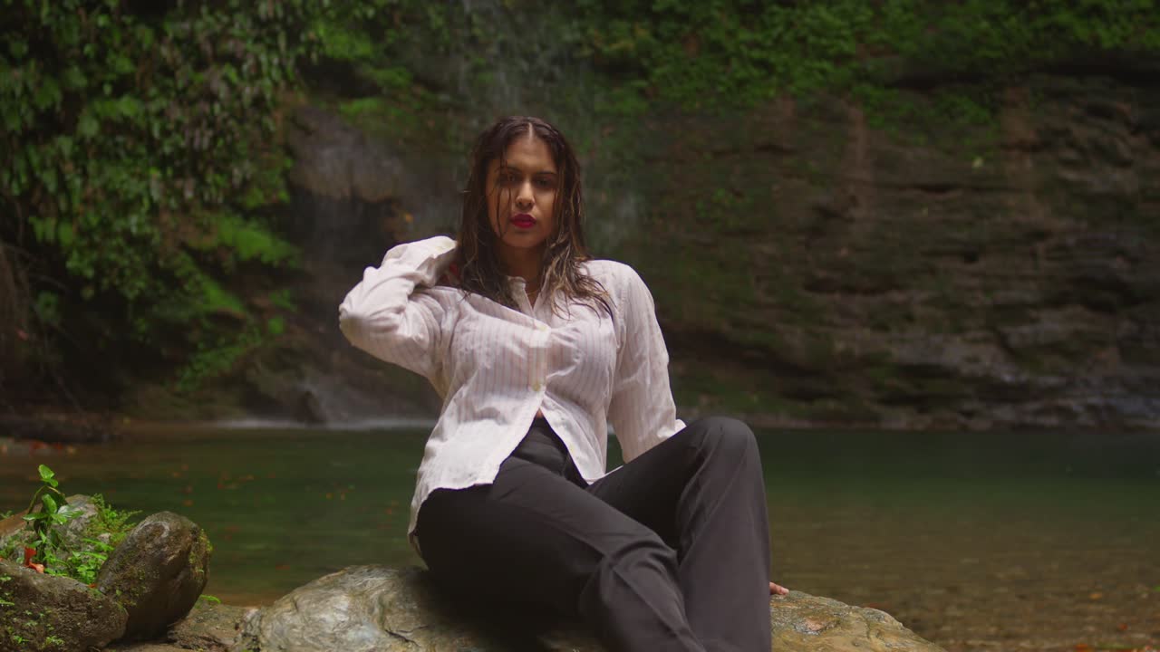 Una ragazza in bikini presso una cascata tropicale.