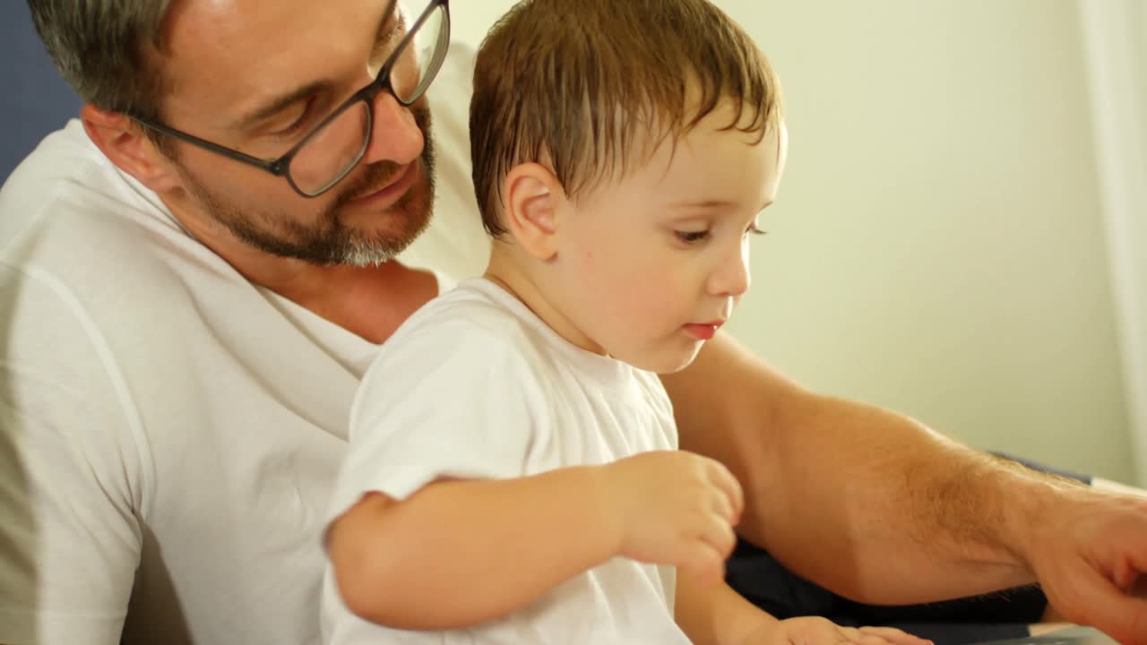 padre e hijo leyendo un libro en la cama en casa 4k