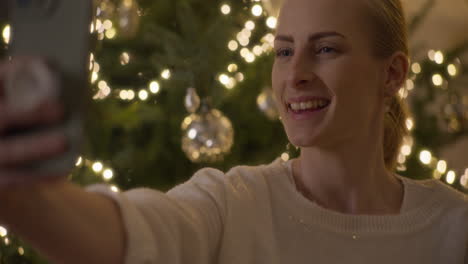 woman taking a selfie by the christmas tree