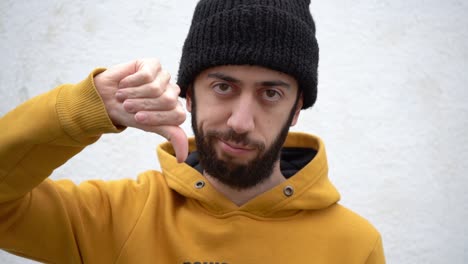 thumbs down signal shown by a man in bonnet hat and yellow clothing