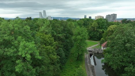 Scenic-Basel-city-skyline-approached-form-the-green-park-landscape-drone-dolly-forward-up-pan