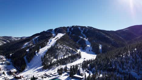 aerial drone shot of ski runs in the mountains with pine trees
