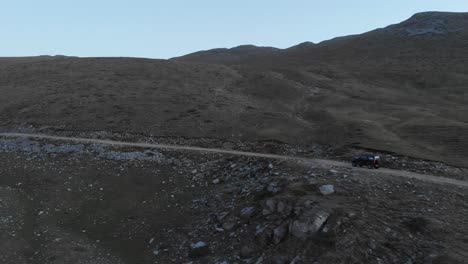 Video-De-Drones-Siguiendo-El-Seguimiento-De-La-Conducción-De-Automóviles-Todoterreno-En-Un-Camino-De-Tierra-De-Montaña-Rocosa-En-El-Monte-Olimpo-Grecia-Al-Anochecer-Panorámico-A-La-Izquierda