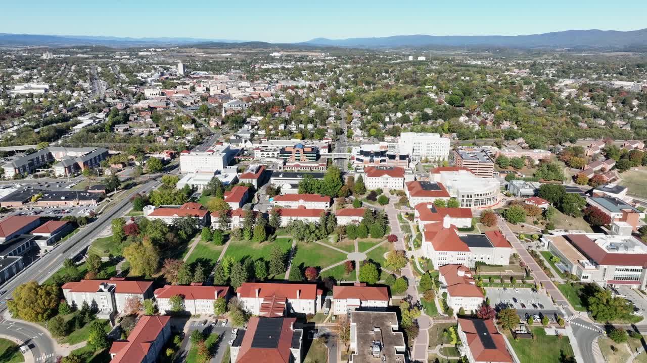 Aerial orbit shot of Harrisonburg City with beautiful James Madison University during sunny day in Virginia. Wide shot. Sunny day in fall season. American town with neat inner yard
