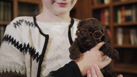 happy child in the library are a girl and a puppy with glasses. cute pets and education