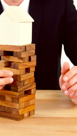 businessman placing wooden block on a tower