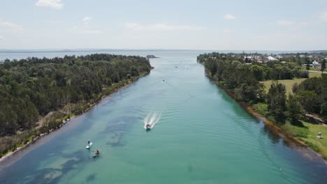 An-aerial-shot-overlooking-boats-and-swimmers-in-the-channel-at-The-Entrance-North,-NSW,-Australia