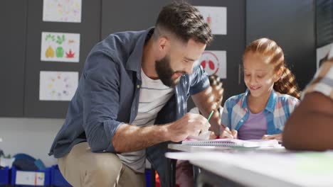 maestro masculino diverso y escolares felices sentados en el escritorio en el aula de la escuela