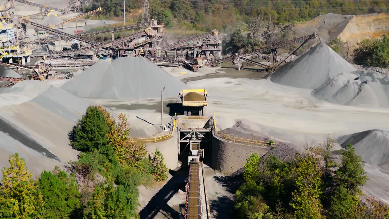 Aerial pullback from dump truck loading hopper and conveyor line at quarry