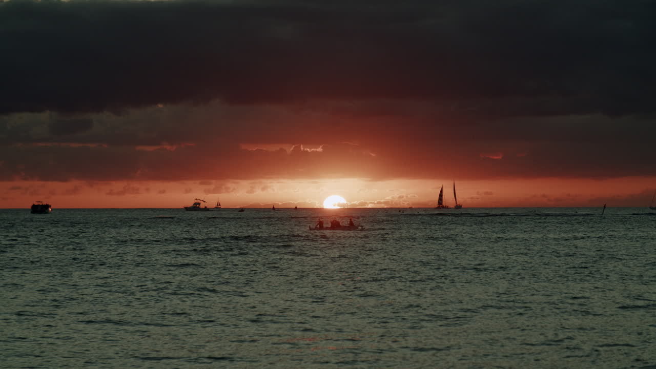 Tropical Sunset with Silhouetted Boats and People on the Water