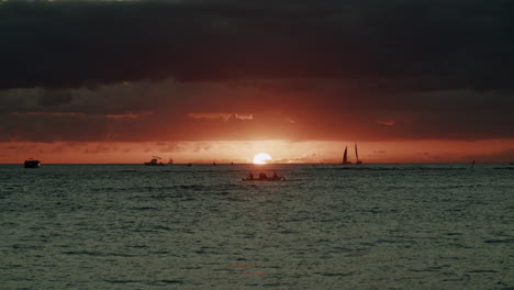 tropical sunset with silhouetted boats and people on the water