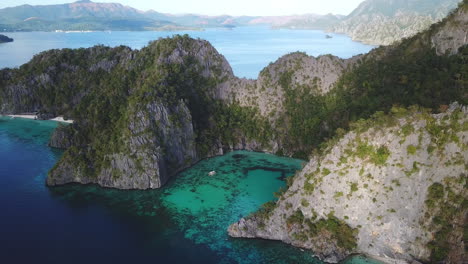 coron island wilderness with sheer drop cliffs and clear blue ocean waters, aerial pull back