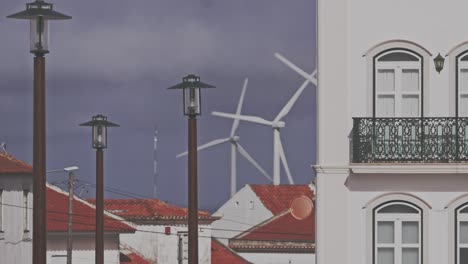 Windmills-in-background-of-Nazare-city,-Portugal,-houses-and-rooftops,-day-view