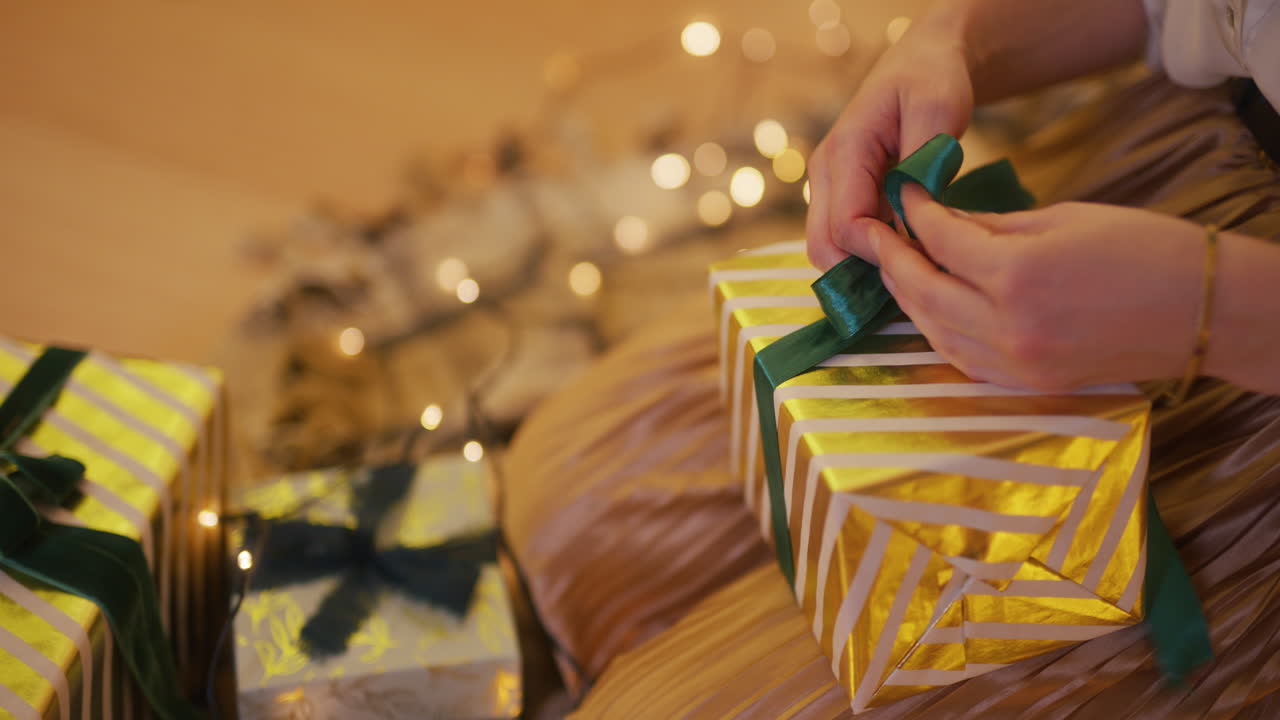 금색 선물을 포장하고 리본을 는 여자의 손의 클로즈업