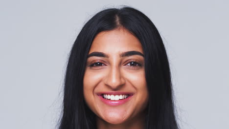 cabeza y hombros foto de estudio de una mujer sonriendo a la cámara en cámara lenta