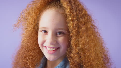 Retrato-De-Estudio-De-Una-Chica-Sonriente-Con-El-Pelo-Rojo-Sobre-Fondo-Púrpura