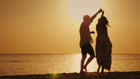 Silhouettes-Of-A-Young-Couple-Cool-Dancing-Against-The-Backdrop-Of-The-Sea-And-The-Setting-Sun-Merry