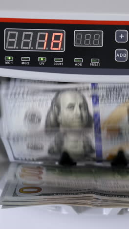 money counting machine with 100 dollar banknotes. us national paper currency. bank automatic equipment for calculation paper currency, finance concept vertical video
