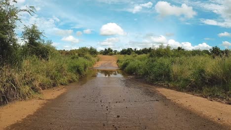 POV-Eines-Fahrzeugs,-Das-Auf-Eine-Niedrige-Brücke-Zufährt-Und-Durch-Sie-Hindurchfährt,-Mit-Regenwasser-Im