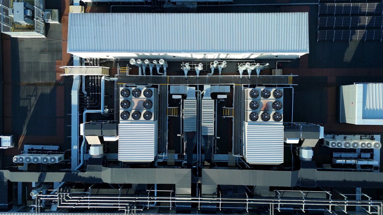 Aerial view of industrial HVAC units and cooling fans on a commercial rooftop, featuring symmetrical ventilation systems.