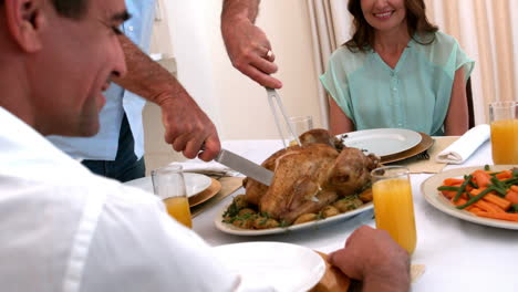 grandfather carving chicken at dinner table