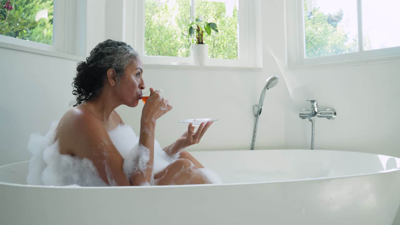 Woman lifting teacup and sipping in tub, gazing windows, animated leaf circling tub for wellness